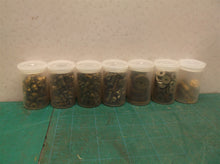 7 small jars of assorted clock parts